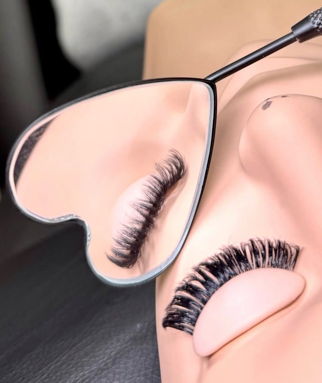 Lash extension practice on a training mannequin with a heart-shaped mirror